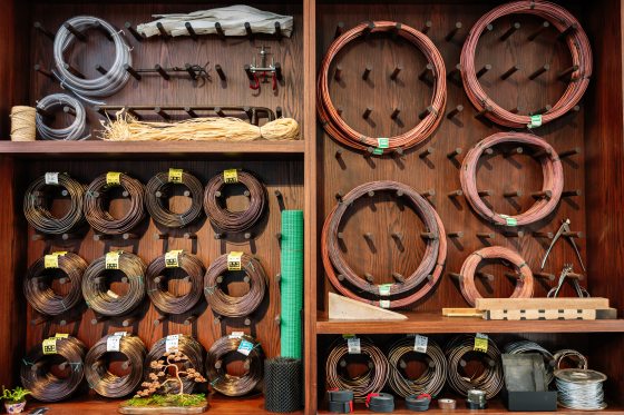 A wood wall with rolls of wiring in different sizes hanging on pegs. 
